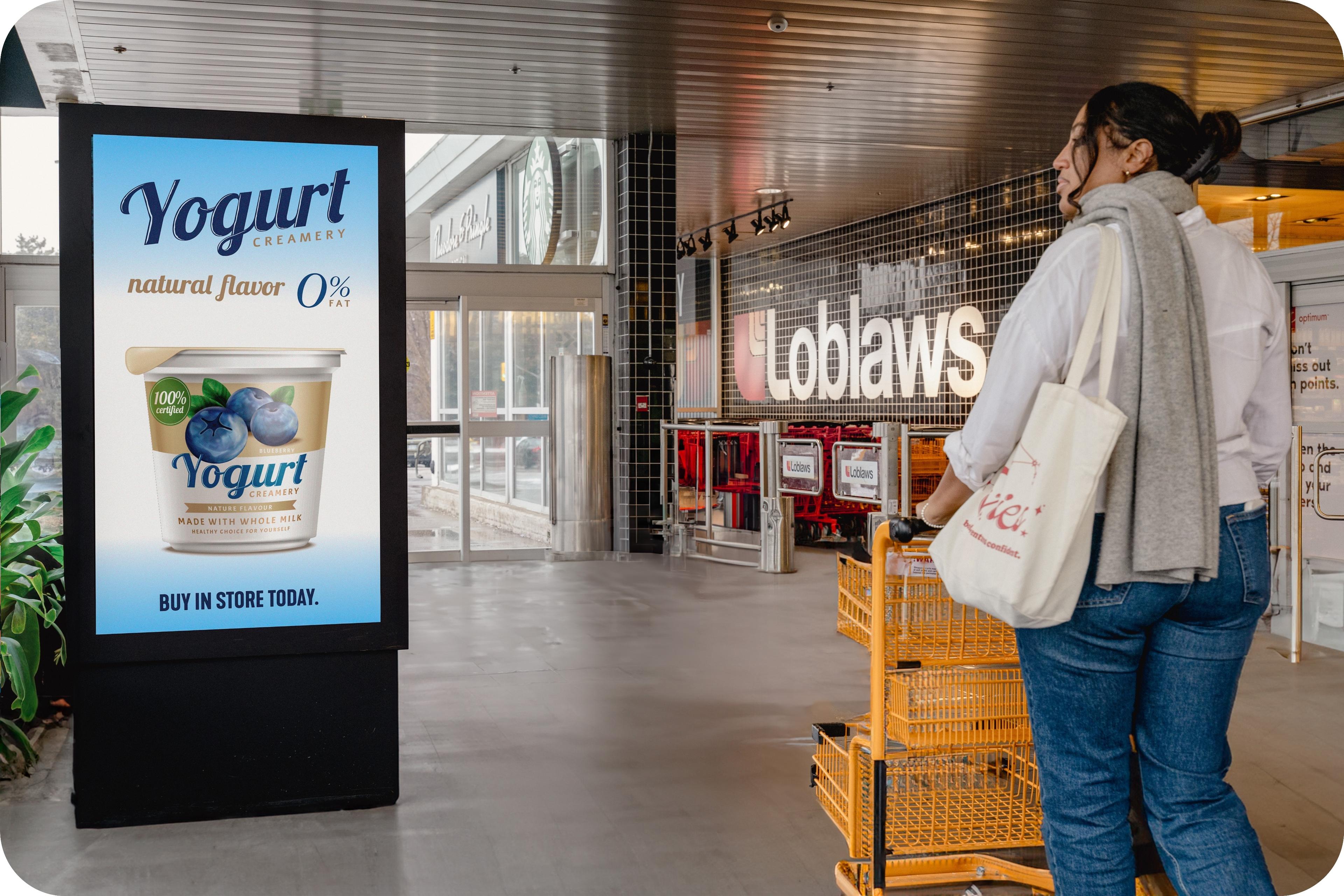 person pushing cart by digital screen in grocery store