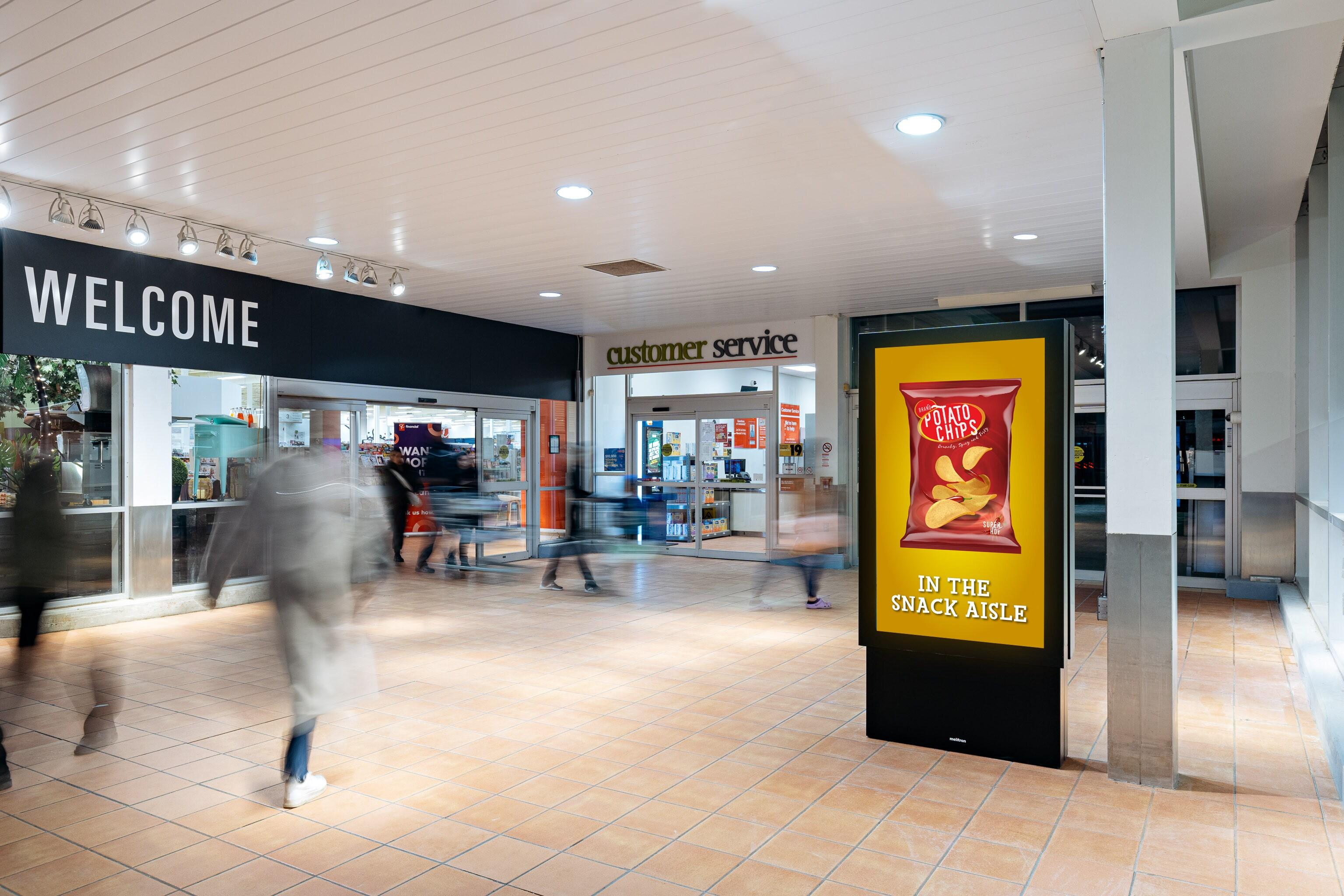 Un écran à l’entrée principale d’une épicerie avec une publicité sur des croustilles.